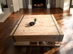 a wooden table sitting on top of a hard wood floor next to a fire place