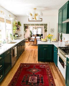 a kitchen with green cabinets and white counter tops, an area rug on the floor