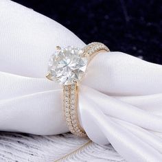 a diamond ring on top of a white napkin with a bow tie around the band