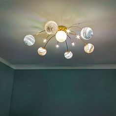 a room with a green wall and a ceiling light that has glass globes on it