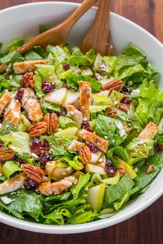 a salad with chicken, apples, cranberries and pecans in a white bowl