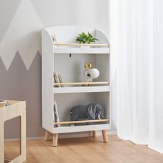 an elephant toy is sitting on top of a book shelf in a child's room