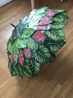 an umbrella made out of leaves and flowers on a wooden floor next to a table