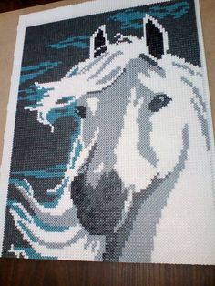 a cross - stitch picture of a white horse with blue eyes on it's face