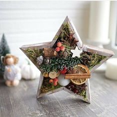 a wooden star decoration with pine cones, oranges and other decorations