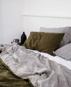 an unmade bed with green and white sheets