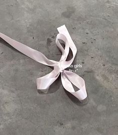 a white ribbon is laying on the ground with it's end curled up and ready to be tied