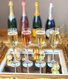 four champagne flutes are lined up on a tray