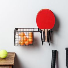 a ping pong racket hanging on the wall next to a tennis ball and racquet