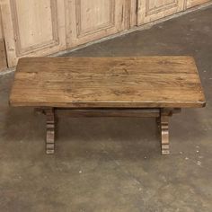 a wooden bench sitting on top of a floor next to a wall with doors in the background