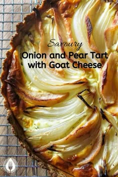 an onion and pear tart with goat cheese is shown on a cooling rack in front of a wooden table