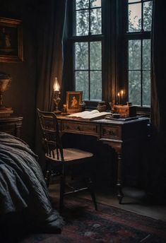 an old fashioned desk and chair in front of a large window with candles on it