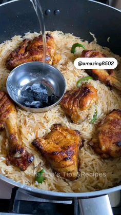 chicken and rice being cooked in a wok with a ladle on the side