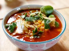 a bowl filled with soup and garnish on top of a wooden table,