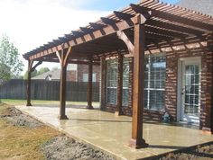 an outdoor covered patio with brick walls and wooden pergols on the side of it