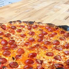 a pepperoni pizza sitting on top of a wooden table