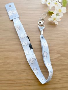 a white lanyard with sheep on it next to flowers