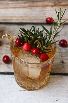 a glass filled with ice and cranberries on top of a wooden table