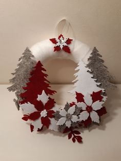 a christmas wreath made out of felt with red and white snowflakes on it