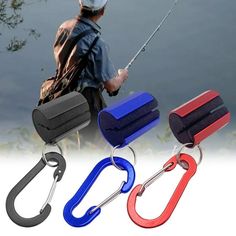 three different colors of fishing hooks on the side of a body of water with trees in the background