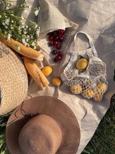 an assortment of fruits and vegetables laid out on the ground next to a straw hat