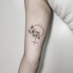 a cross and flowers tattoo on the arm