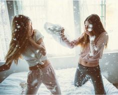 two young women standing in front of a window with snow falling all over the floor