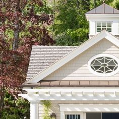 a white house with a clock on the top of it's roof and trees in the background