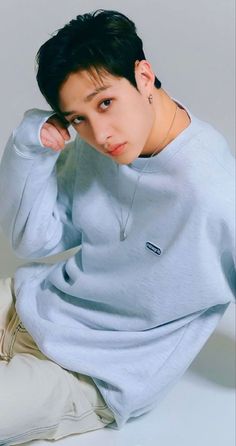 a young man sitting on the ground wearing a blue sweatshirt