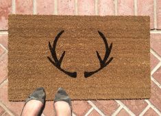 a person standing in front of a door mat with antlers on it