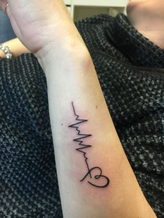 a woman's arm with a heartbeat tattoo on it