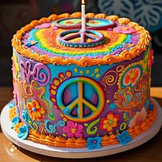 a brightly colored cake with a lit candle on it's top and peace sign decoration