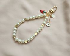 a white beaded bracelet with a strawberry charm