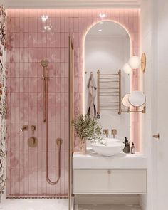 a bathroom with pink tiles and gold fixtures on the walls, along with two sinks