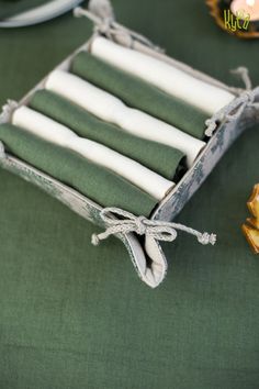 four candles in a box on a green table cloth next to some other items and decorations