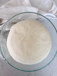 a glass bowl filled with dough on top of a table