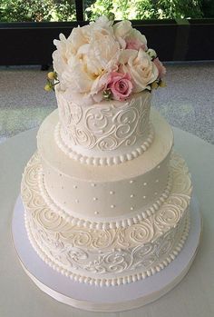 a three tiered wedding cake with white frosting and pink flowers on the top