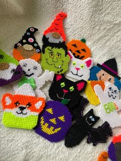 a group of knitted halloween themed items on a white blanket with pumpkins, witches and cats