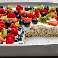 a close up of a cake in a pan with berries and kiwis on top