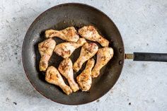 chicken is cooking in a frying pan on the table