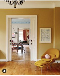 a yellow chair sitting in the middle of a living room next to a table and chairs