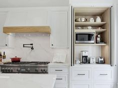 a kitchen with white cabinets and marble counter tops, along with open shelving above the stove