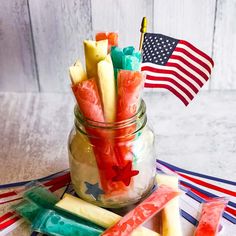 a mason jar filled with candy sticks and an american flag