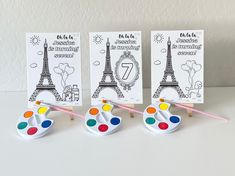 three small eases with paintbrushes in front of the eiffel tower