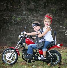 two children are sitting on a red motorcycle