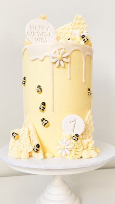 a yellow cake with white frosting and honeycombs is on a pedestal in front of a white wall