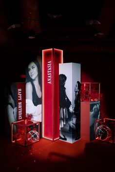 an exhibit with red lighting and black and white images on the walls, in front of a dark background