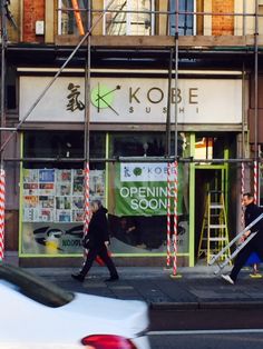 two people walking down the street in front of a building with scaffolding on it