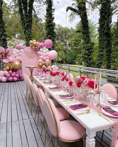 a table set up with pink and gold balloons, place settings and plates for an event