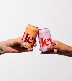 two people holding up cans of beer with the word jely written on one can